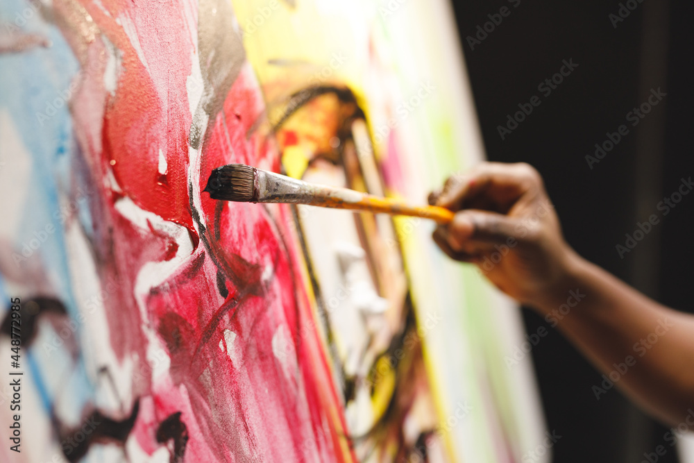 Close up of african american male painter at work painting on canvas in art studio - obrazy, fototapety, plakaty 