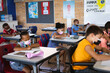 © WavebreakMediaMicro - Group of students wearing face masks studying while sitting on their desks at elementary school
