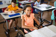 © WavebreakMediaMicro - Portrait of disabled african american girl smiling while sitting on wheelchair at elementary school