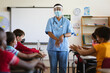 © WavebreakMediaMicro - Female health worker showing students to use hands sanitizer at elementary school