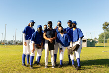 Portrait Of Diverse Group Of Female Baseball Players And Coach In Face Masks Standing On Sunny Field