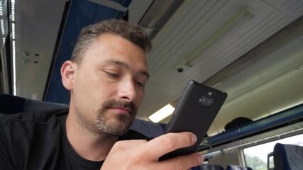 Attractive middle aged man on train using his phone, low angle