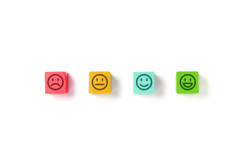 Emoticon faces in colors wooden blocks over white background. Service evaluation and satisfaction survey concepts. Angry, neutral, good mood and happy. Copy space. Flat lay photo