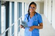 © Serhii - portrait of friendly, smiling confident female healthcare professional with lab coat, arms crossed holding glasses. Isolated hospital clinic background.