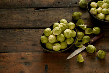 Wall Mural - Top view shot of fresh green Brussels sprouts in bowls placed on rustic wooden table