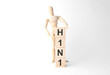 Wooden mannequin near tower of cubes with word h1n1 on table against light background