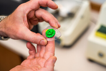 Wall Mural - Production of glasses. The master inserts the lenses into the eyepiece frame