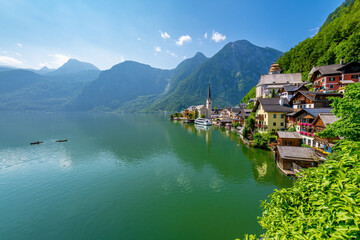 Hallstatt, Austria ; August 9, 2021 - A scenic picture postcard view of the famous village of Hallstatt reflecting in Hallstattersee lake in the Austrian Alps.