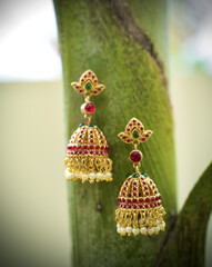 Wall Mural - Close up of a two decorated earrings with green white background