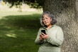 © McKinsey Jordan/Stocksy - Senior Woman in Park Takes a Moment to Check Her Phone