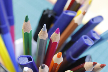 Poster - Closeup of colorful sharp pencils and markers under the lights with a blurry background