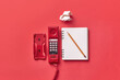 © Yaroslav Danylchenko/Stocksy - Vitage red telephone handset and notebook