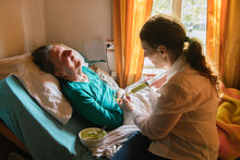 Social Worker Feeding Senior Woman In The Bed
