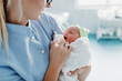 © hedgehog94 - Young nurse standing in maternity ward and holding newborn baby in her arms. After birth concept.