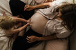 © Samantha Gehrmann/Stocksy - toddler moisturises mothers pregnant stomach