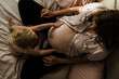 © Samantha Gehrmann/Stocksy - toddler moisturises mothers pregnant stomach
