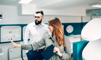 Middle age man choosing utensils for his home bathroom and female seller helps him to make right decision