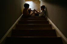 Two Boys Playing Cards On The Stairs