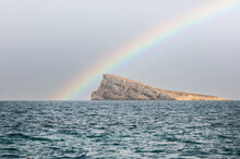 Rock In Calm Blue Sea And Rainbow Background
