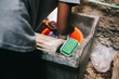 © David Prado/Stocksy - Faceless person doing laundry by hands in concrete reservoir