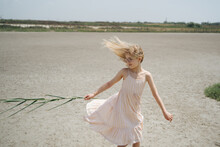 Little Girl In Dress Playing On The Sand