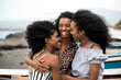 © David Prado/Stocksy - beautiful african sister women embracing with the ocean background