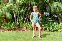 Little Girl In A Swimsuit Standing In Her Yard
