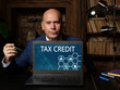 © Yurii Kibalnik - Business concept about TAX CREDIT with inscription on the laptop. Business photo shows a dollar-for-dollar reduction of the income tax you owe