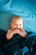 Adorable boy in the bedroom. A newborn baby is resting in a blue-colored bed. Textiles and bedding for children. Family morning at home. Selective focus.
