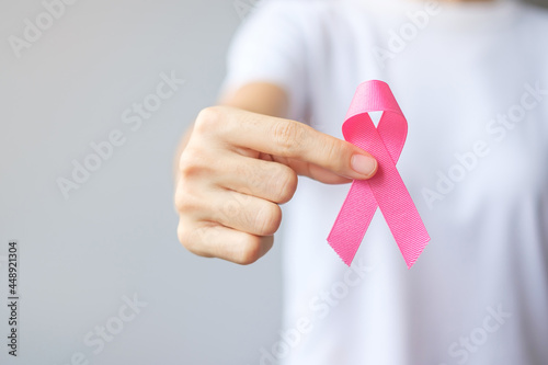 October Breast Cancer Awareness month, elderly Woman in white T- shirt with hand holding Pink Ribbon for supporting people living and illness. International Women, Mother and World cancer day concept