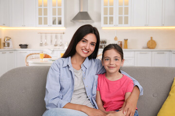 Canvas Print - Portrait of happy mother and daughter on sofa at home. Single parenting