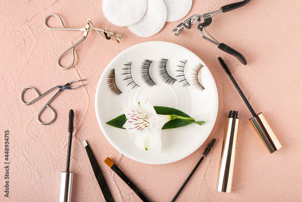 Composition with false eyelashes, mascara and tools on color background