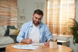 © New Africa - Young man coloring antistress picture at table indoors