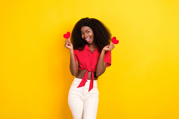 Wall Mural - Portrait of attractive cheerful girl holding in hands small little heart shape isolated over bright yellow color background