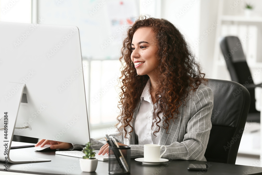 Beautiful young woman working with computer in office