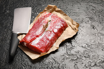 Raw beef brisket and butcher knife on dark background