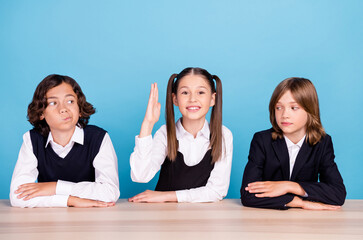 Sticker - Photo of sweet doubtful schoolkids formalwear smiling sitting table arms folded looking for answer isolated blue color background