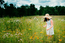 Side View Of Girl Standing In Field By Flowering Plants