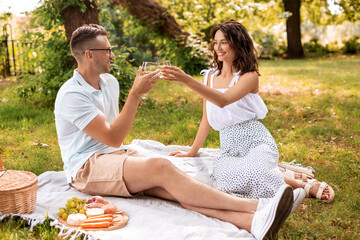 Wall Mural - leisure and people concept - happy couple with drinks and food having picnic at summer park