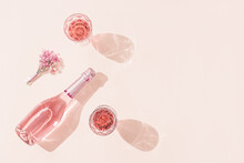 Bottle Of Rose Wine, Two Glasses With Drink, Small Bouquet Of Flowers In Bright Sunlight. Summer Romance Concept.