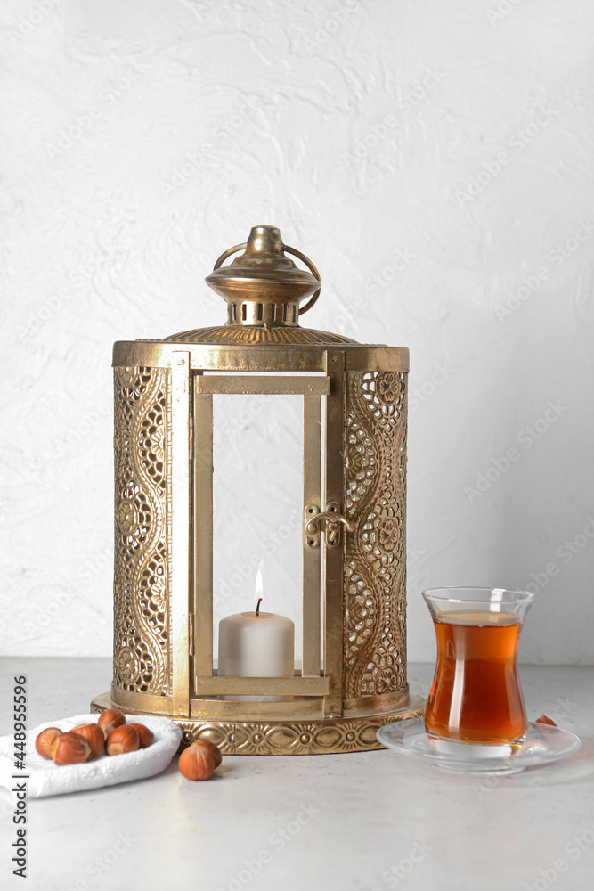 Muslim lantern with nuts and Turkish tea on light background