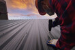 © RooM The Agency - Construction worker installing metal sheets on a roof, Thailand