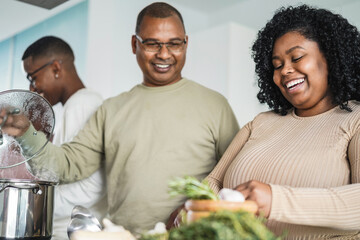 Happy black family cooking inside kitchen at home -Focus on daughter face