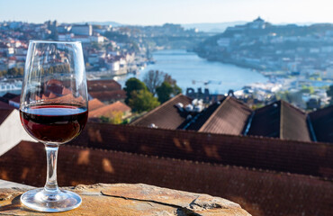 Tasting of different fortified dessert ruby, tawny port wines in glasses with view on Douro river, porto lodges of Vila Nova de Gaia and city of Porto, Portugal