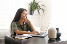 Cheerful Indian Young Woman Using Laptop Computer For Remote Work At Home Office. Smiling Mixed-race Businesswoman In Casual Wear Holding Video Call, Typing Email, Chatting Online With Colleagues