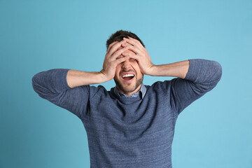 Wall Mural - Man suffering from terrible migraine on light blue background