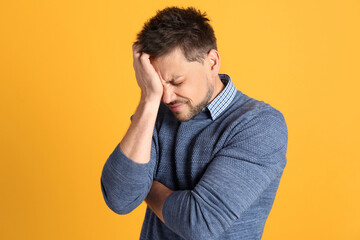 Wall Mural - Man suffering from terrible migraine on yellow background