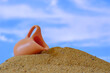 small jug lying in the sand on a sky background