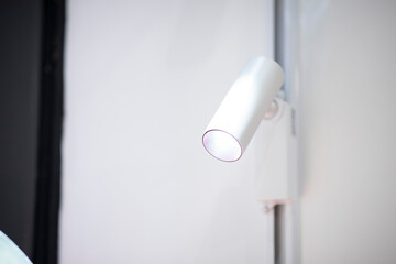 White lamp on a white wall. Part of the interior. Lighting in a cafe. Background with light source. Shines down.