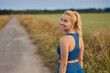 Attractive fit healthy woman turning to smile at the camera as she prepares to work out jogging along a rural footpath in a healthy active outdoor lifestyle concept